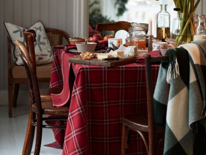 Das Bild zeigt eine festlich gedeckte Tafel für ein Weihnachtsessen mit einem rot-weiß karierten Tischtuch.