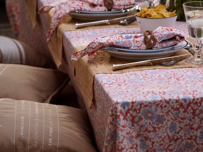 Gedeckter Tisch mit korallefarbener Tischdecke im floralen Dessin